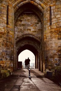 Rear view of people walking in corridor of historic building