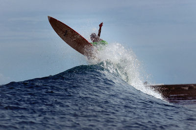 Man surfing in sea against sky