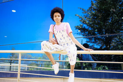 Portrait of young woman standing on railing