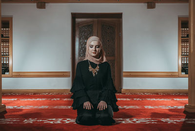 Woman in traditional clothing praying at mosque