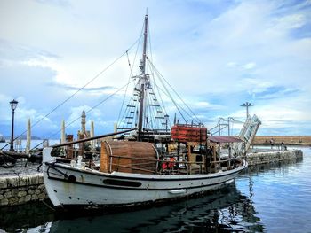 Boats moored at harbor against sky