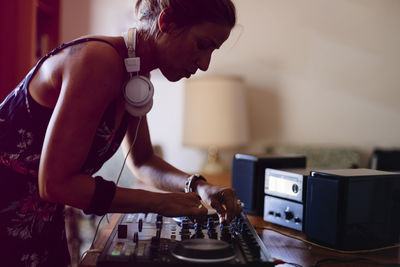 Side view of female dj mixing sound while standing in recording studio