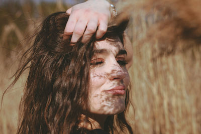 Close-up of young woman with hand in hair looking away