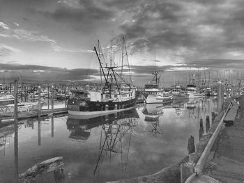 Boats moored at harbor against sky