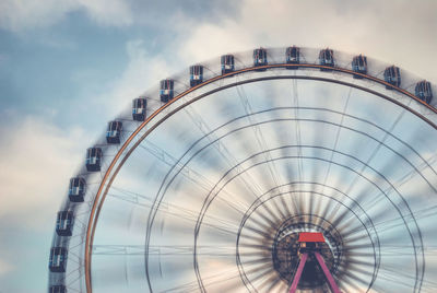 Low angle view of ferris wheel against cloudy sky