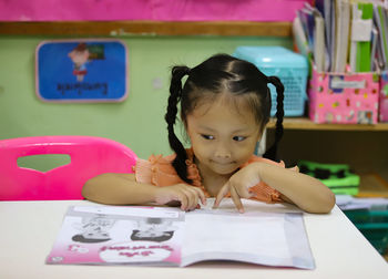 Portrait of cute girl with book on table