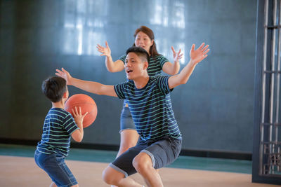 Family playing basketball on sports court