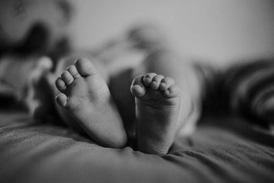 Low section of baby lying on bed