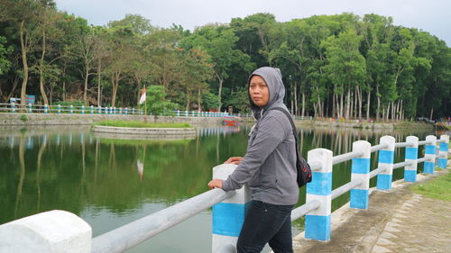 Side view of man standing by lake against trees