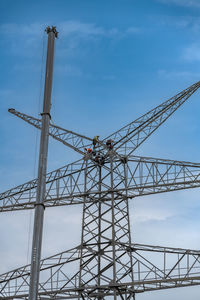 Workers assembling a power pole at high altitude