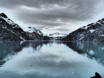 Scenic view of lake by snowcapped mountains against sky