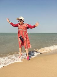 Full length of woman standing on beach against sky