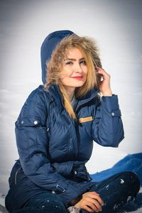 Portrait of smiling woman sitting in park during winter