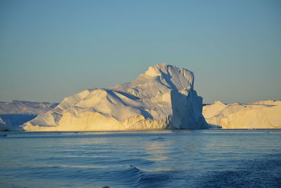 Scenic view of sea against clear sky with beautiful icebergs in the midnight sun ilulissat greenland