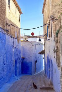 Street amidst buildings against blue sky