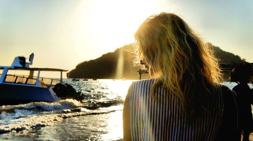 Rear view of woman standing by sea against sky