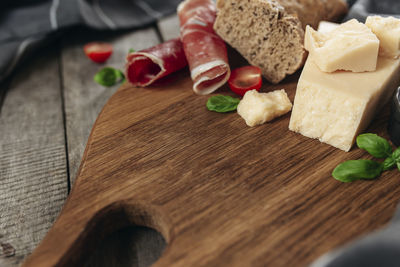 Italian cuisine concept. cutting board, parmesan cheese chunks, thinly sliced ham, cuts of tomatos