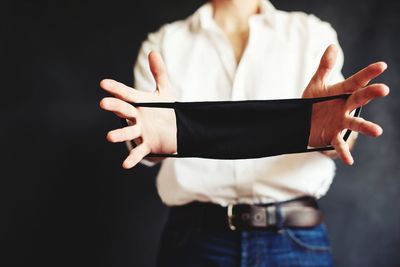 Midsection of woman standing against black background
