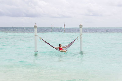 Woman with umbrella on sea against sky