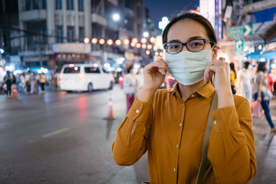 Portrait of young woman standing on street in city