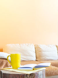 Close-up of yellow and book on table against wall