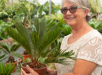 Portrait of smiling woman holding potted plant