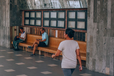 Rear view of people sitting on wall