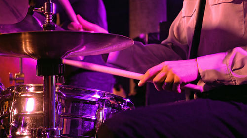 Midsection of man playing drum during music concert