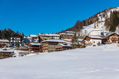 Winter in sauris di sotto. traditional architecture under the sun and snow