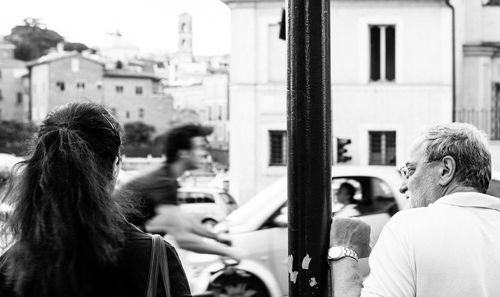 Man and woman standing by pole on street in city