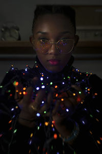 Portrait of woman holding illuminated lighting in darkroom