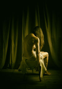 Woman from behind sitting on a stool covered with goatskin ii