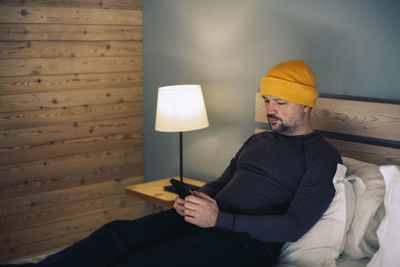 Portrait of young woman using mobile phone while sitting on bed at home