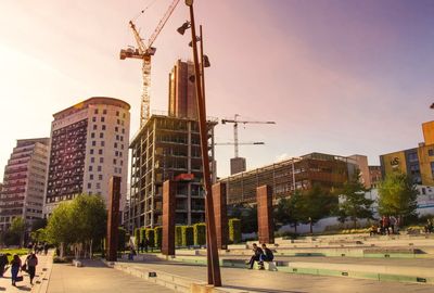 People at construction site in city against sky