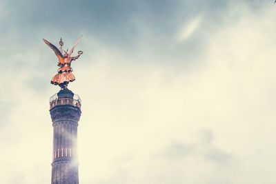 Low angle view of angel statue against cloudy sky