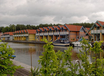 Houses by river against sky