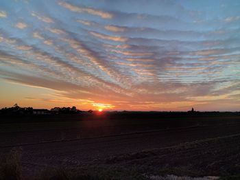 Scenic view of field against dramatic sky during sunset