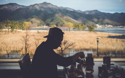 Side view of man having food at table