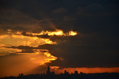 Silhouette buildings against orange sky during sunset