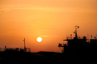 Silhouette cranes against sky during sunset