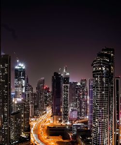 Illuminated modern buildings in city against sky at night