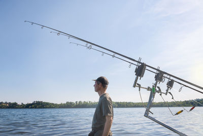 Low angle view of man fishing in sea against sky