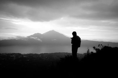 Silhouette man standing on mountain against sky