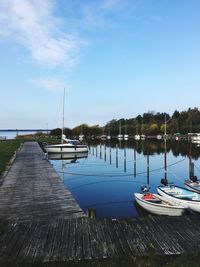 Boats moored in calm sea against blue sky