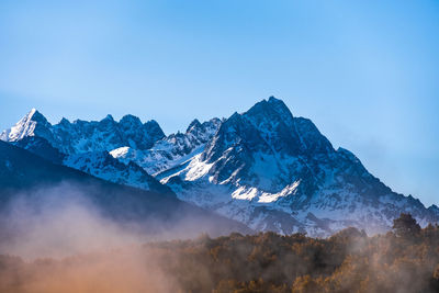 Scenic view of snowcapped mountains against blue sky