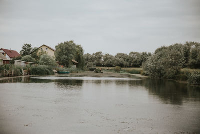 Scenic view of lake by trees and building against sky