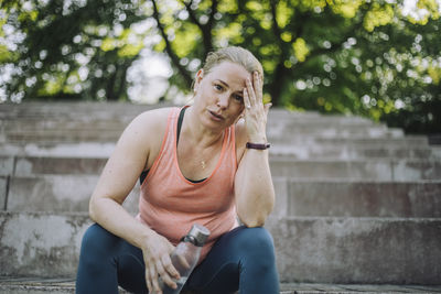 Low angle portrait of tired woman with head in hand sitting on steps