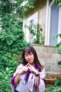 Portrait of a beautiful young woman standing against plants