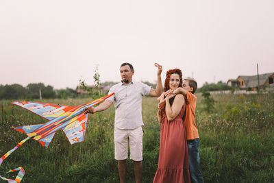 Happy family and children run on meadow with a kite in the summer on the nature.