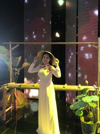 Woman standing by glass at night